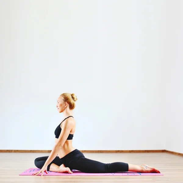 Beautiful caucasian woman exercising yoga indoors — Stock Photo, Image