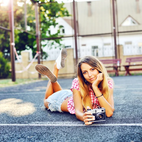 Hermosa chica sonriente acostada en el suelo con una vieja cámara retro — Foto de Stock