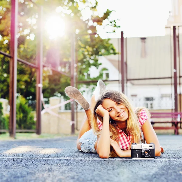 Hermosa chica sonriente acostada en el suelo con una vieja cámara retro —  Fotos de Stock