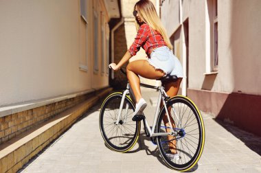 Spor geri genç seksi kadın sabit vites bisiklet üzerinde outd poz