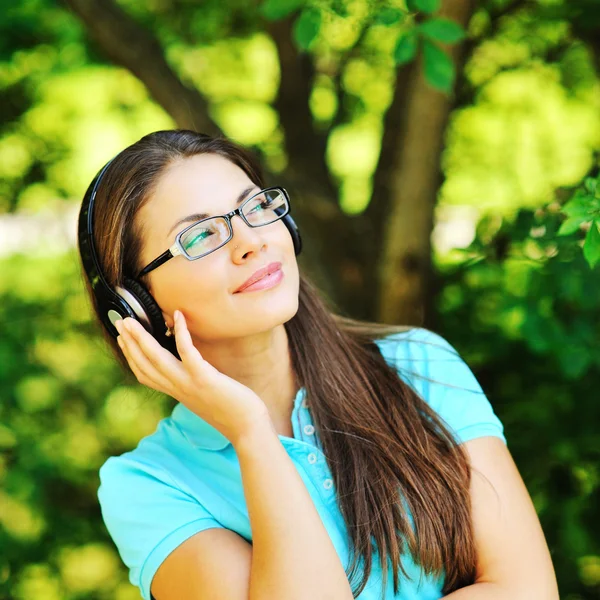 Schöne Mädchen genießen Musik in einem grünen Sommerpark — Stockfoto