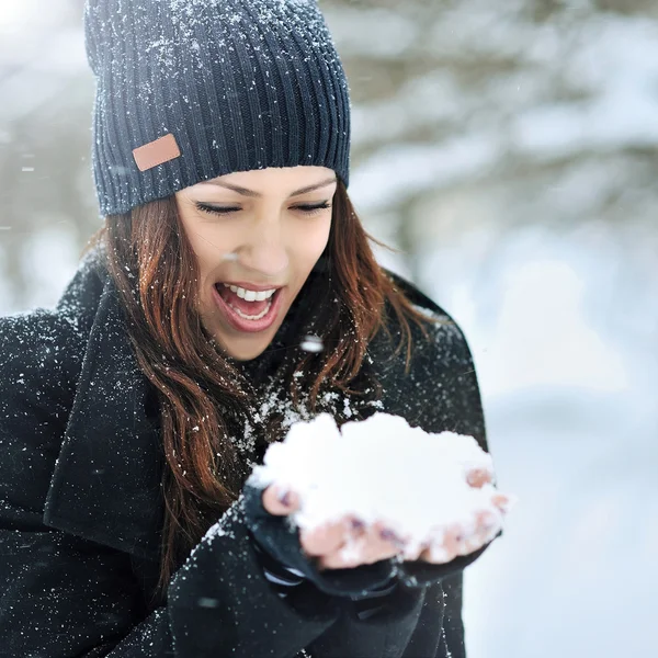 Jonge lachende vrouw spelen met sneeuw in de winter park — Stockfoto