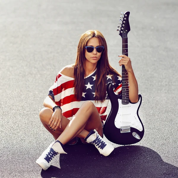 Beautiful and fashion young woman posing with electric guitar — Stock Photo, Image