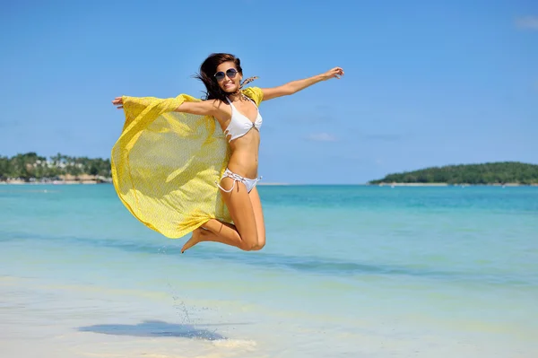 Menina bonita com cachecol amarelo pulando na praia. Viajar um — Fotografia de Stock