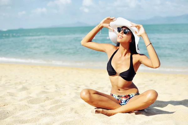 Plajın kumları üzerinde oturan bir mayo güzel kadın — Stok fotoğraf