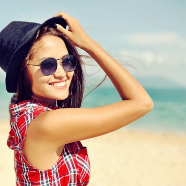 Şapka ve güneş gözlüğü güzel gülümseyen kadın kapatmak