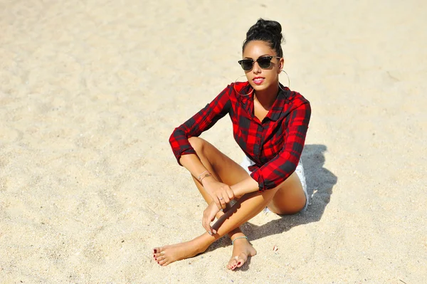 Mulher de óculos de sol sentada na areia — Fotografia de Stock