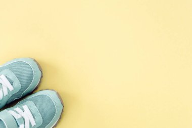 Sarı pastel arka planda yeşil spor ayakkabılar, boşluğu kopyala.