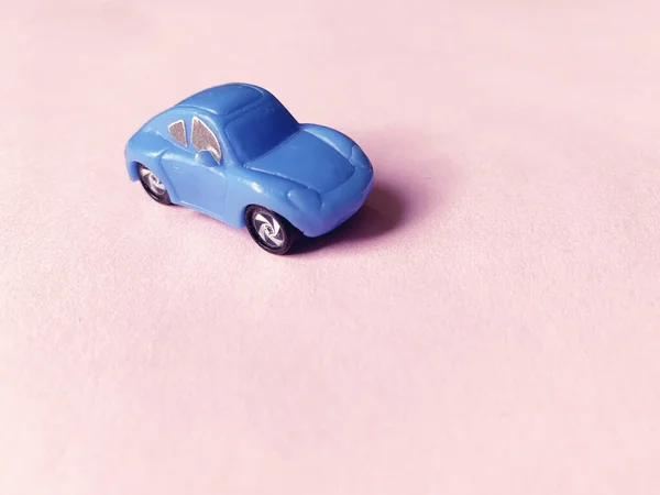 blue toy car on pink paper background