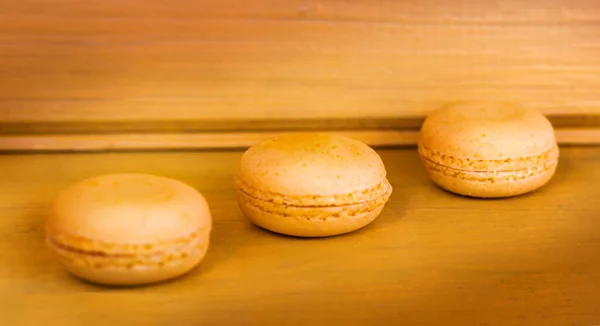 Drie Gele Heerlijke Macarons Een Gele Houten Achtergrond — Stockfoto