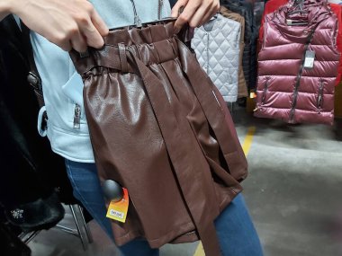 Bir kız mağazadan deri bir etek seçer, kendini dener..