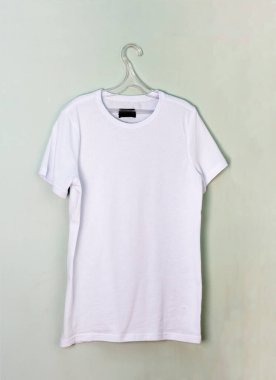 Açık renkli bir duvarda beyaz boş bir tişört.