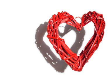 Sevgililer Günü. Büyük kırmızı hasır bir kalp havada süzüldü, beyaz arka planda bir gölge bıraktı..