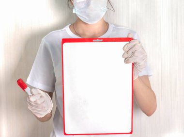 Maskeli ve eldivenli bir kız boş bir A4 posteri tutuyor..