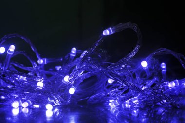 Karanlık bir arka planda mor renkte noel ışıkları.