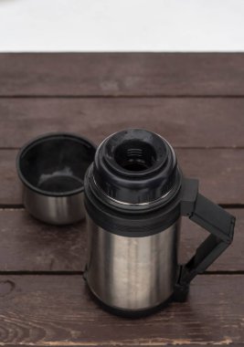 Açık hava termosu ve kahve kış manzaralı bir bankta..