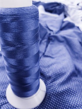 Kapalı kumaş renginde nakış işlemek için parlak mavi bir iplik makarası..