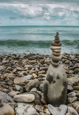 Bulutlu bir günde kumsaldaki deniz taşlarından yapılmış uyum kulesi..