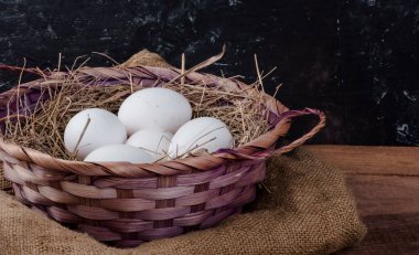 Bir sepet beyaz tavuk yumurtası ve saman kırsal bir arka plan..