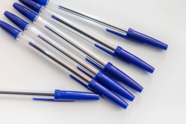 Beyaz arka planda mavi başlıklı tükenmez kalemler.