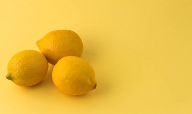 Sarı arka planda üç sarı limon ve boşluğun bir kopyası..
