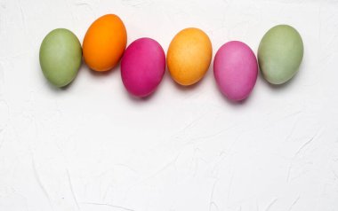 Beyaz desenli arka planda parlak paskalya yumurtaları ve boşluğun bir kopyası..