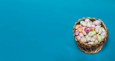 Mavi arka planda sepette renkli yuvarlak şekerler.