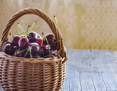 Masadaki sepetin içinde olgun kirazlar ve boşluğun bir kopyası..