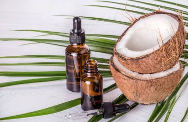 Coconut oil with coconut on a palm leaf background on a white table.
