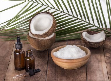 Coconut oil with coconut shavings on a palm leaf background on a wooden table.