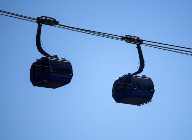 Bu resim farklı yönlere giden iki kabini olan modern bir teleferiği gösteriyor..