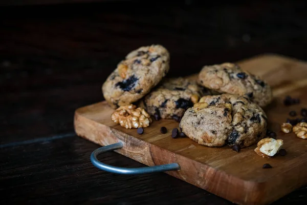 Biscoitos de chocolate com nozes no fundo da placa de corte de madeira — Fotografia de Stock