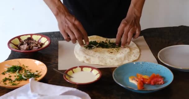 Mens mãos preparando e embrulhando envoltório shawarma tradicional ou giroscópio com carne, legumes e molhos — Vídeo de Stock