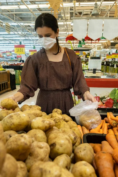 Alarmed female wears medical mask against coronavirus while shopping in store- health, safety and pandemic concept - young woman wearing protective medical mask for protection from virus