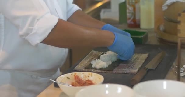 Mains d'homme chef préparant des sushis japonais sur un tapis de feuille de bambou — Video