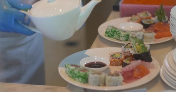 Närbild av händer med handskar förbereder och serverar japansk sushi. Kock häller sojasås i tallriken på restaurang. — Stockvideo