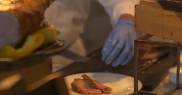 Szef kuchni rzeźbi kawałek pieczonego mięsa i serwuje na talerzu do gościa. Usługi cateringowe podczas wesela, imprezy lub spotkania biznesowego — Wideo stockowe