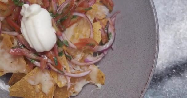 Plaat van verse nacho 's met ui, tomaten, jalapeno, kaas en saus. Traditionele Mexicaanse aperitiefhapje — Stockvideo