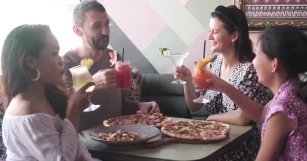 Group of young multiethnic friends eating, talking, clinking glasses and laughing in restaurant or cafe during summer — Stock video