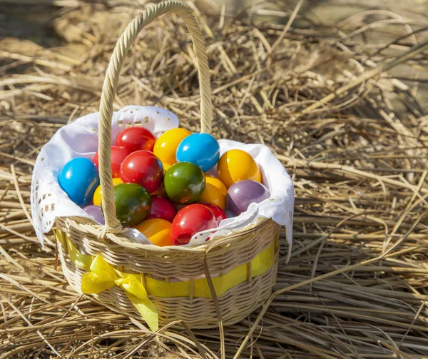 Œufs de Pâques colorés à l'intérieur en osier de paille, sur paille — Photo