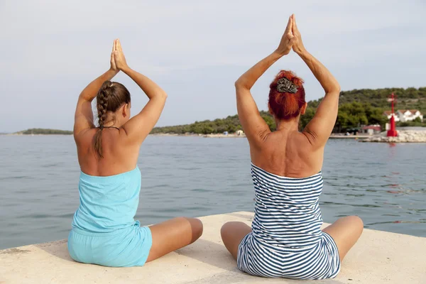 Mother and daughter performing joga on sunny beach — Stock Photo, Image