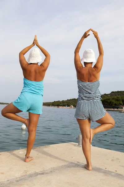 Mother and daughter performing joga on sunny beach — Stock Photo, Image