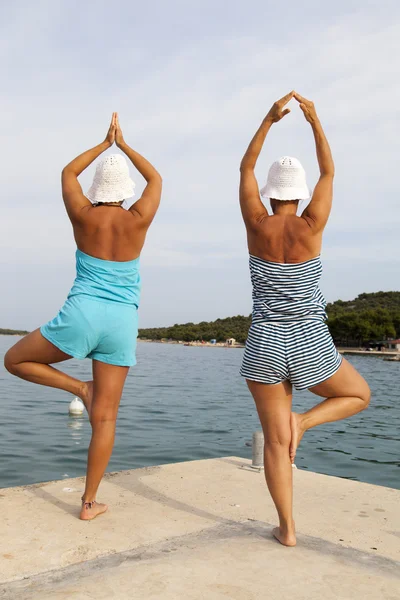 Mère et fille exécutant joga sur la plage ensoleillée — Photo