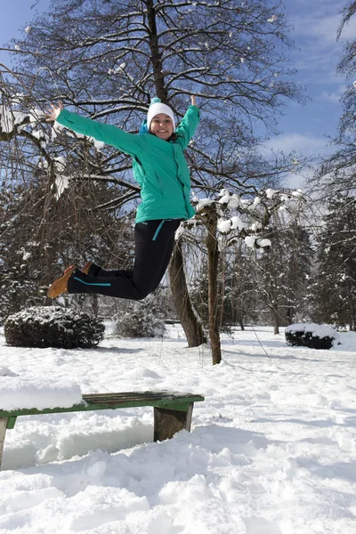 Mujer joven sonriente saltando en un día soleado de invierno — Foto de Stock