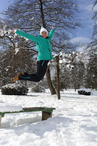 Sorridente giovane donna che salta in una giornata invernale soleggiata — Foto Stock