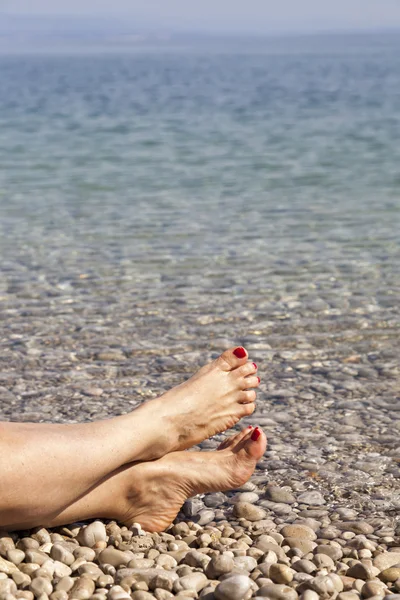 Ett par mänskliga ben på havet kusten — Stockfoto