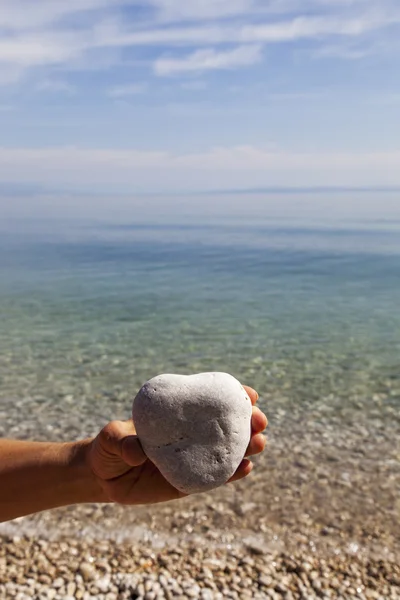 Mano sosteniendo una piedra natural en forma de corazón — Foto de Stock