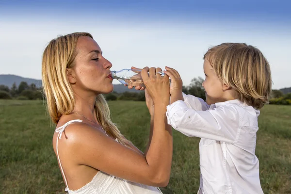 Söta mor dricksvatten samtidigt leker med hennes son — Stockfoto