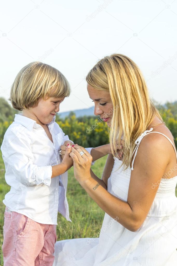 Crying young boy showing finger injury to his concerned mother