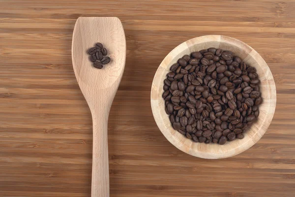 Granos de café en tazón sobre fondo de madera — Foto de Stock